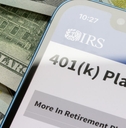401(k) plans IRS site on phone with cash background