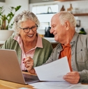 Older couple smiling while working on financial paperwork