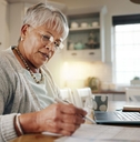 senior woman doing paperwork with laptop