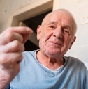 Old man in his 80's showing something on his hands and smiling