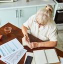 Older woman doing taxes on the kitchen table