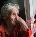 Sad elderly woman looking out window