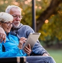 Retired couple on park bench looking at tablet