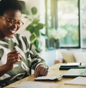 African American woman smiling while doing taxes in her home