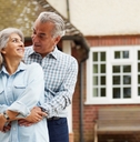 Retired couple hugging in front of the house