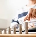 Woman adding coins to the last pile as it slowly shows growth of wealth