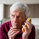 Older man on the phone looking suspicious