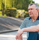 Man in his 50s sitting outdoors looking beyond, thinking