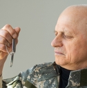 Senior veteran in military uniform holding tag