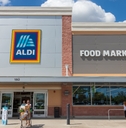 Aldi store front and shoppers coming out of it pushing a cart