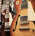row of guitars on display for sale hanging in a music store