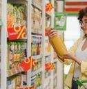 Woman grocery shopping holding orange juice checking the bottle