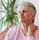 Woman in her 70s looking worried and in pain