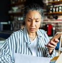 Mature woman on laptop and phone with worried expression