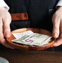 Server holding wood bowl with check and cash tips