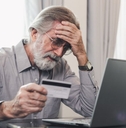 Stressed mature man holding credit card