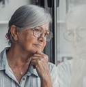 Concerned elderly woman looking out window