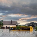 Flooded street with stranded bus and homes around