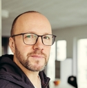 Bald man wearing glasses looking at camera