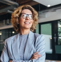 Woman in suit wearing glasses smiling at work