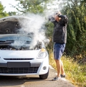 An anxious man near a broken car on the road
