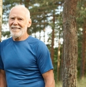 Smiling older man leaning against a tree