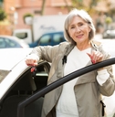 Mature woman standing besides white car