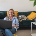woman freelancer working on laptop with her dog at home