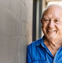 Smiling senior man leaning on concrete wall