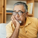 Older man looking worried resting his face on his hand
