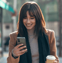 Woman looking at phone and holding coffee