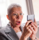 Older woman shocked looking at phone screen