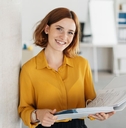 Young office worker in a yellow top holding a binder
