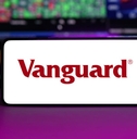 Vanguard displayed on mobile phone with stock market chart background
