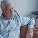 Older man sitting on couch looking distressed