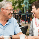 Couple in their 60s sitting outside having coffee