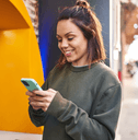 Young woman on mobile phone using outdoor ATM