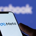 Meta logo on smartphone screen and Facebook logo background