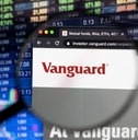 Vanguard company logo on a website with blurry stock market developments in the background