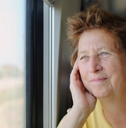 Woman in her late 70s looking through the window