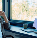 Man thinking with laptop near window