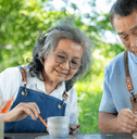 Senior couple doing pottery outside home
