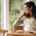 Woman thinking near window with her computer