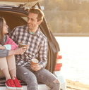 Couple sitting in car on beach while traveling