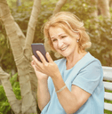 Senior retiree woman looking at investments on phone