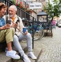 happy senior couple tourists sitting on stairs