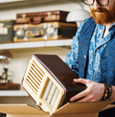 A man places a vintage radio into a cardboard box.