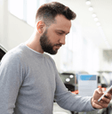 person looking at phone in car dealership