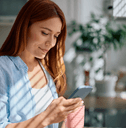 Smiling woman looking at her phone and holding a mug