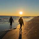 Beach walkers casting long shadows